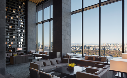 Aman Tokyo lounge with floor-to-ceiling windows overlooking the city skyline and contemporary seating areas.