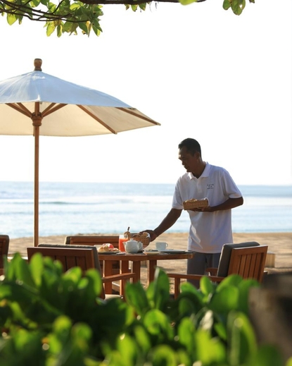 Private butler service at Aman Villas at Nusa Dua, with staff member arranging outdoor seating by the sea.