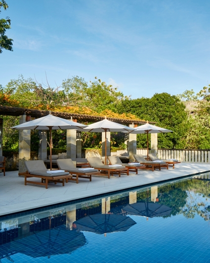 Private swimming pool at Aman Villas at Nusa Dua, with sun loungers beneath cream parasols.