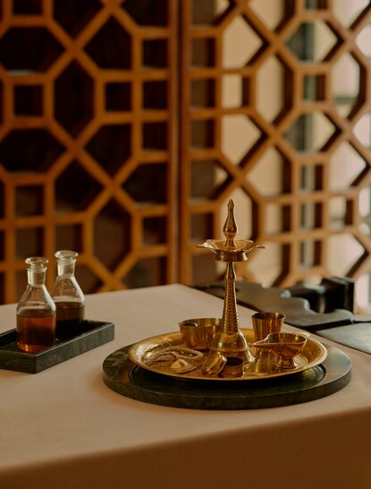 Spa treatment detail at Amanbagh with golden patterned screens and burnished metal vessels on marble surface.