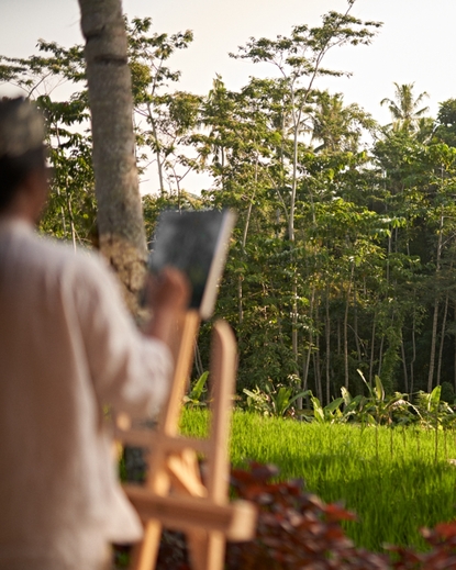 绘画课程参与者在安缦黛宁度假村的户外空间中作画，背景为郁郁葱葱的绿色景观。