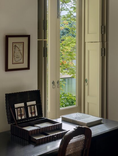 Garden bedroom at Amangalla with tall windows overlooking verdant grounds and period furnishings.