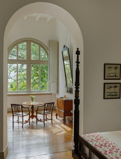 Arched doorway leading to a chamber at Amangalla, with wooden furniture and natural light from a curved window.