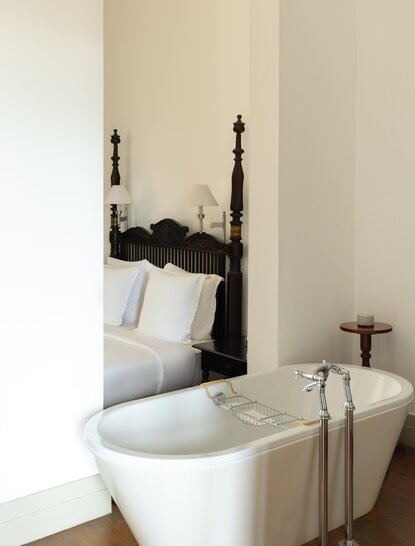 Freestanding bathtub beside a four-poster bed at Amangalla, Sri Lanka.