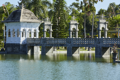 安缦丘澜度假村的蓝色水门楼，倒映在平静的水面上，周围是棕榈树。