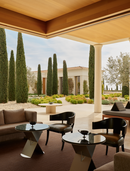 Resort bar lounge at Amanzoe with cypress trees and Greek landscape views.