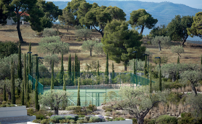 Tennis court at Amanzoe surrounded by Mediterranean gardens and cypress trees, Greece.