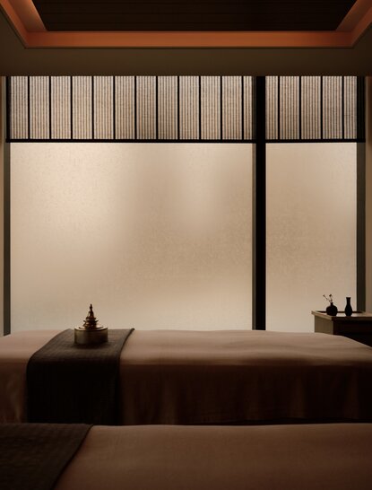 Serene spa bathing area at Aman Nai Lert Bangkok with wooden soaking tub and softly lit window panels.