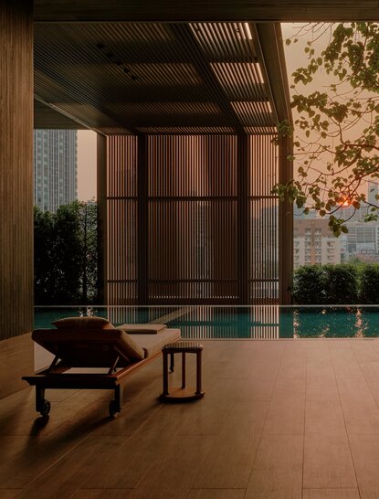 Wellness swimming pool at Aman Nai Lert Bangkok, with serene water and minimalist wooden architecture.