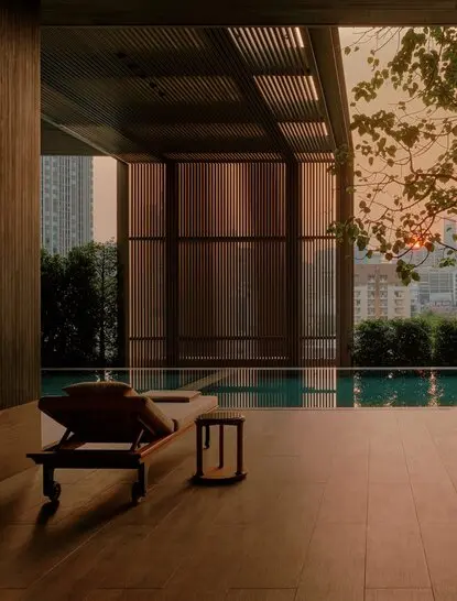 Wellness swimming pool at Aman Nai Lert Bangkok, with serene water and minimalist wooden architecture.