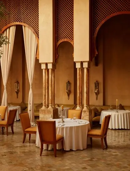 Moroccan restaurant at Amanjena with arched doorways, terracotta columns, and round dining table.