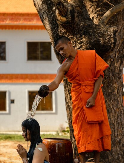 Buddhist monk in saffron robes receiving water blessing at Amansara, Cambodia.