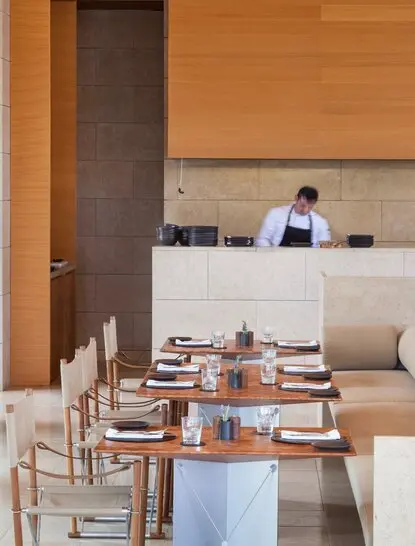 Dining pool restaurant at Amanzoe resort in Greece, with wooden interiors and set tables overlooking the water.