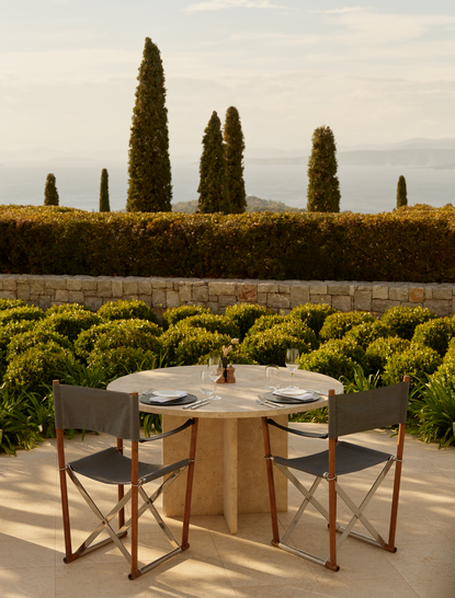 アマンゾイのメインレストランで、糸杉に囲まれたテラス席に配置された2脚の椅子とテーブル。