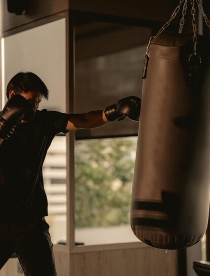 一位拳击手在曼谷奈乐安缦酒店的健身房内训练泰拳,挥拳击打沙袋。