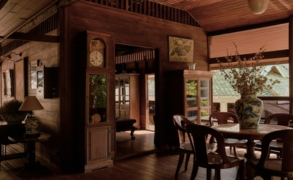 Warm-toned dining room at Aman Nai Lert Bangkok with wooden furnishings and traditional Thai architectural details.