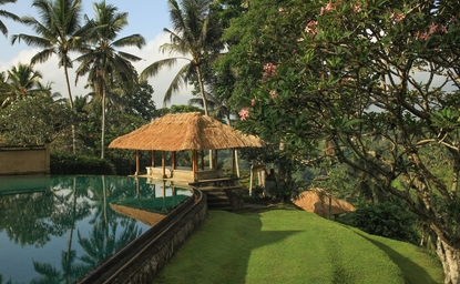 Amandari's swimming pool pavilion surrounded by lush greenery and reflected in still water at dusk.