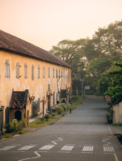 Colonial-era yellow buildings line a quiet pathway at Amangalla in Galle Fort, Sri Lanka.