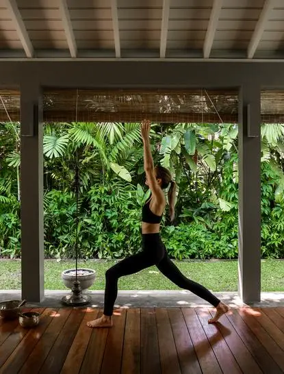 Woman practising yoga in the open-sided pavilion at Amangalla, Sri Lanka, surrounded by lush greenery.