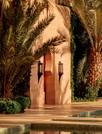 安缦珍纳度假村主宅入口，粉色拱门由棕榈树框架，摩洛哥建筑风格。