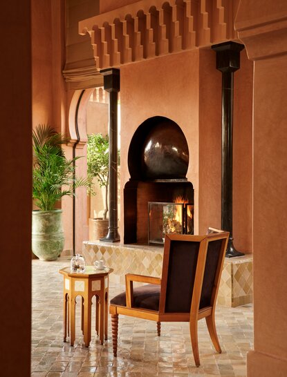 安缦珍纳度假村的Al-Hamra套房内，壁炉旁摆放着黑色椅子和小茶几。