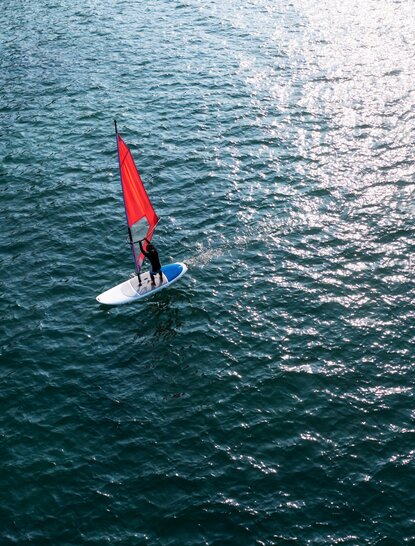 Kite surfer with red sail on turquoise waters at Amanoi resort, Vietnam.
