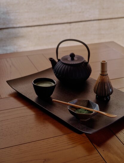 Japanese tea ceremony setup at Aman Le Mélézin, featuring black kettle, cup and wooden serving tray.