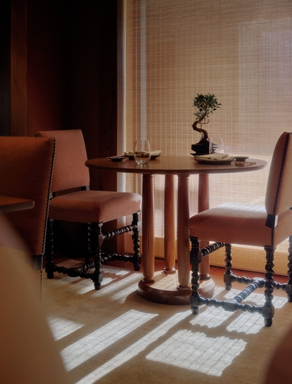 Intimate dining area at Aman Le Mélézin with wooden table, rust-coloured chairs, and geometric floor pattern.