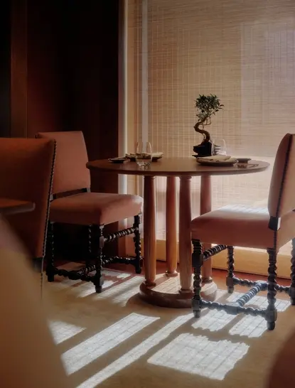 Salle à manger au restaurant d'Aman Le Mélézin avec table ronde et chaises en cuir cognac.