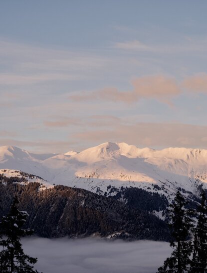 Aman Le Mélézin resort views: snow-capped Alpine peaks rising above morning mist, French Alps.