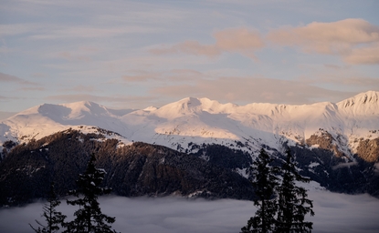 Aman Le Mélézin resort views, snow-covered alpine landscape at dusk with mountains on horizon.