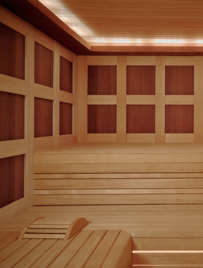 Sauna en bois avec bancs et éclairage chaleureux à Aman Le Mélézin.