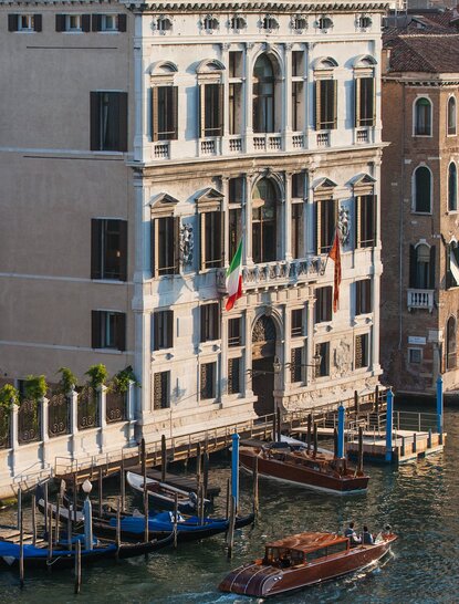 Palazzo Papadopoli façade at Aman Venice hotel, with gondolas moored along the Grand Canal below.