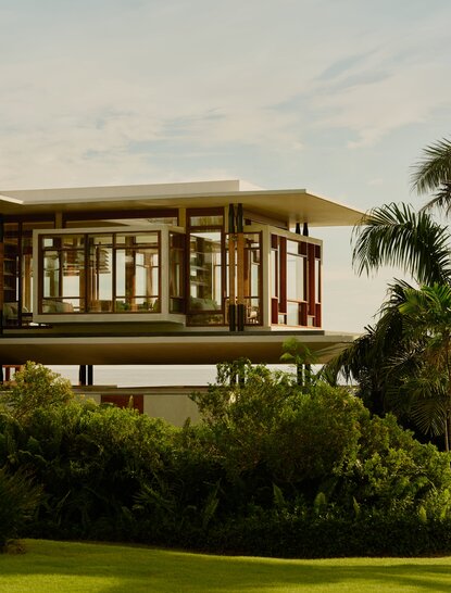 Amanera's Casa Grande exterior elevated on stilts amid lush tropical gardens at dusk.