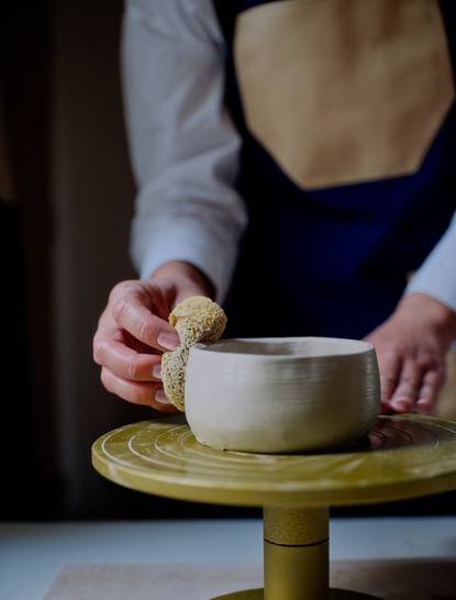 Participant's hands shaping clay during a ceramics art class at Amanzoe resort, Greece.