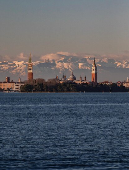 Venice's basilicas and church spires rise across the lagoon at sunrise, viewed from Aman Rosa Alpina.