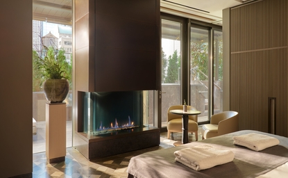 Spa treatment room at Aman New York with fireplace, natural light, and serene wellness setting.