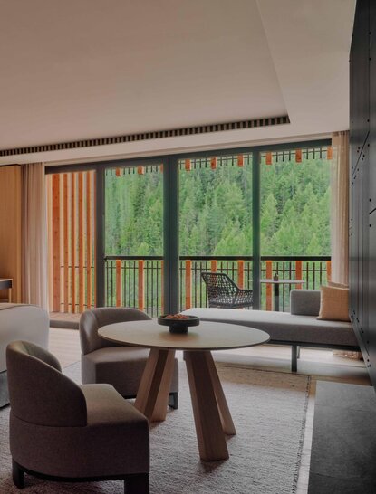 Junior Suite with seating area overlooking Alpine woodland at Aman Rosa Alpina, Italy.