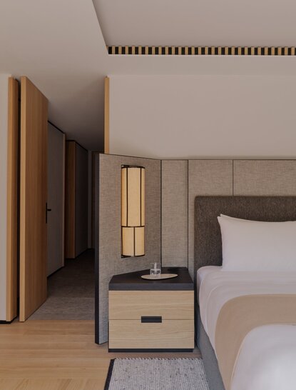 Aman Suite bedroom at Aman Rosa Alpina with wooden wardrobe, bedside table, and soft lighting.