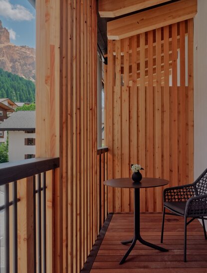 Deluxe Room balcony at Aman Rosa Alpina resort, with wooden shutters and mountain views.