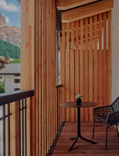 Deluxe Room balcony at Aman Rosa Alpina resort, with wooden shutters and mountain views.