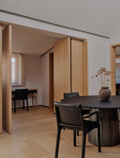 Suite at Aman Rosa Alpina resort with wooden partition, desk, chair and warm lighting.