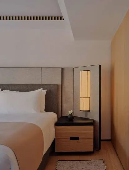 Premier Suite bedroom at Aman Rosa Alpina resort, with bed and wooden bedside table with lamp.