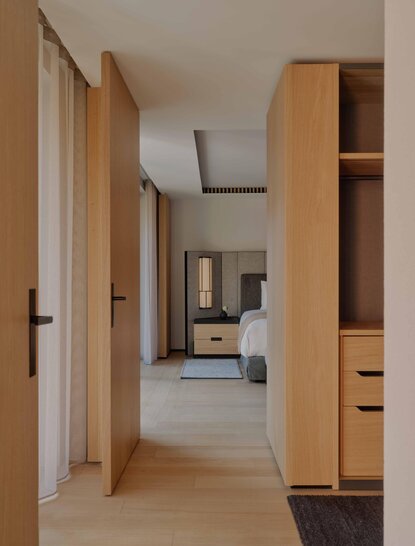 Entrance hallway of a Premier Suite at Aman Rosa Alpina resort, featuring light wood cabinetry and corridor leading to bedroom area.