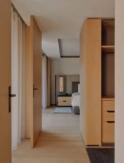 Entrance hallway of a Premier Suite at Aman Rosa Alpina resort, featuring light wood cabinetry and corridor leading to bedroom area.