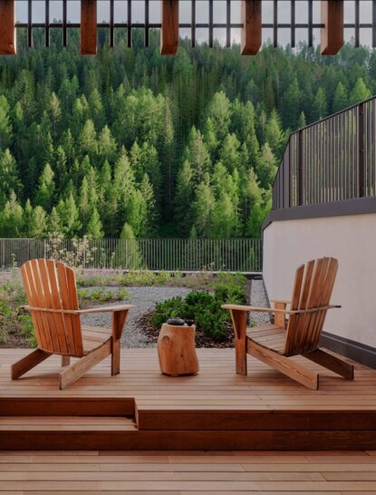 Rosa Alpina Suite terrace with wooden chairs overlooking Alpine forest at Aman Rosa Alpina resort.