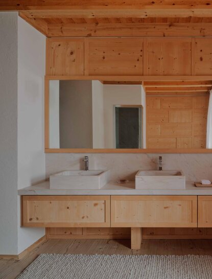 Zeno Suite bathroom at Aman Rosa Alpina resort, featuring dual wooden vanities and mirrors.