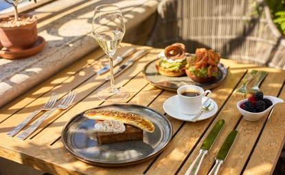 Brunch table at Aman Venice's Garden Restaurant with pastries, coffee, and fresh juice in dappled sunlight.