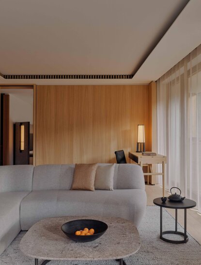 Aman Rosa Alpina suite with wooden-panelled walls, contemporary seating area, and central fireplace.