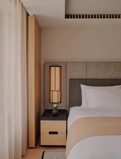 Superior Room at Aman Rosa Alpina, Italy, featuring a bed with bedside table and warm wooden accents.